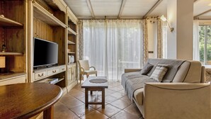 Ein Wohnzimmer mit Fernseher, Sofa und einem kleinen Tisch.