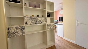 A room with a white built-in shelving unit with multiple compartments, a wooden floor, and a door to the right. - Renovated studio in Lourdes - Rue de la Grotte, near the Sanctuary and the Pyrenees (Lourdes)