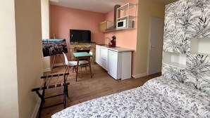 A compact room with a bed, a small dining table, a TV, a microwave, and a wardrobe. - Renovated studio in Lourdes - Rue de la Grotte, near the Sanctuary and the Pyrenees (Lourdes)