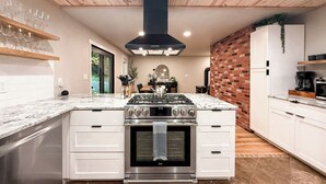 Une cuisine moderne dotée d’un îlot central, d’appareils électroménagers en acier inoxydable et d’un mur décoratif en briques.