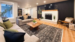 Un salon moderne avec une cheminée, un canapé, une table basse et une bibliothèque.
