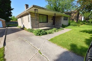 A single-story house with a stone facade, a front porch with a metal railing, and a well-maintained lawn. - Walkable to Notre Dame! Cozy 2 bedroom home(426) (South Bend)