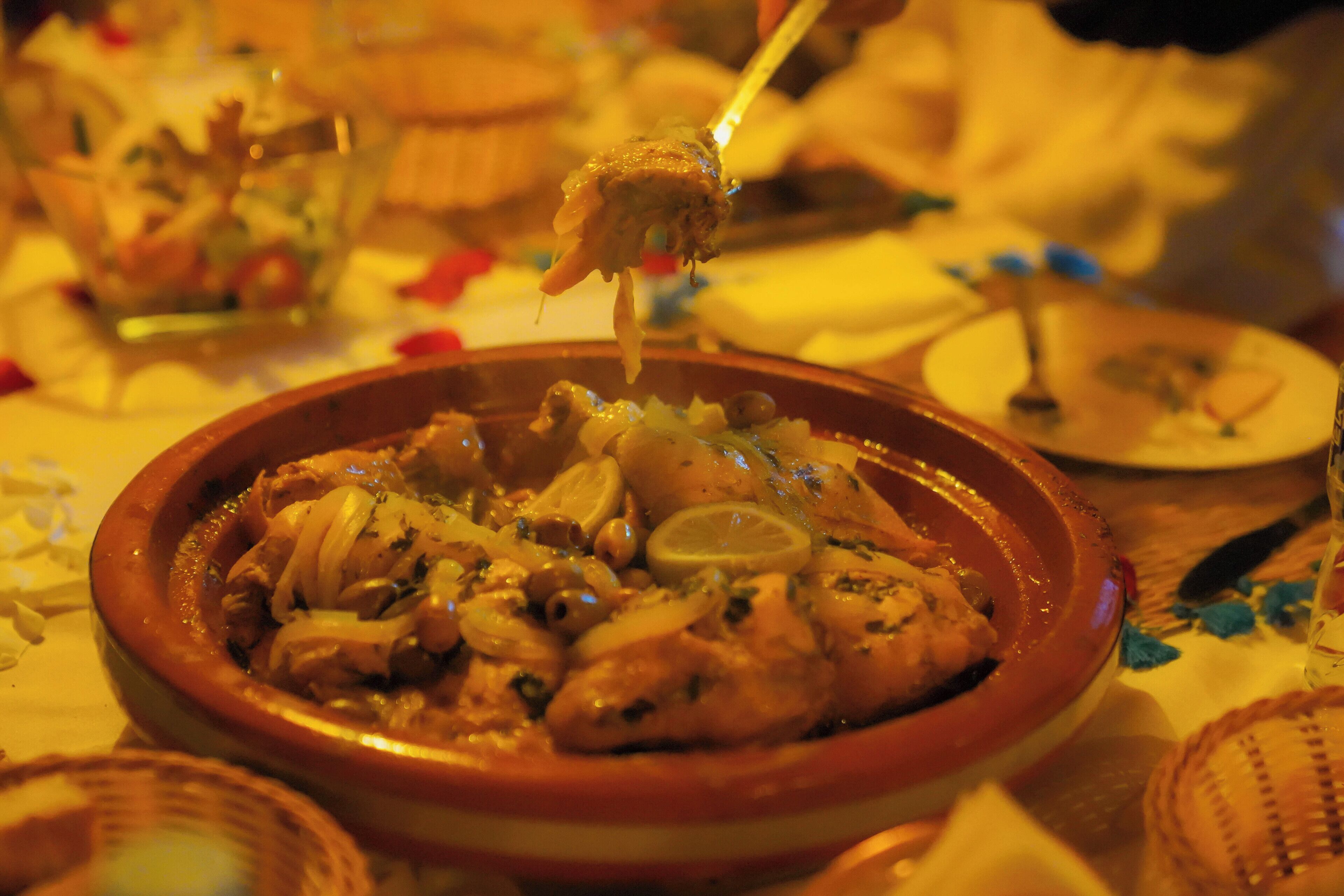 Gros plan d’un plat composé de poulet et de tranches de citron, servi dans un bol traditionnel en argile.