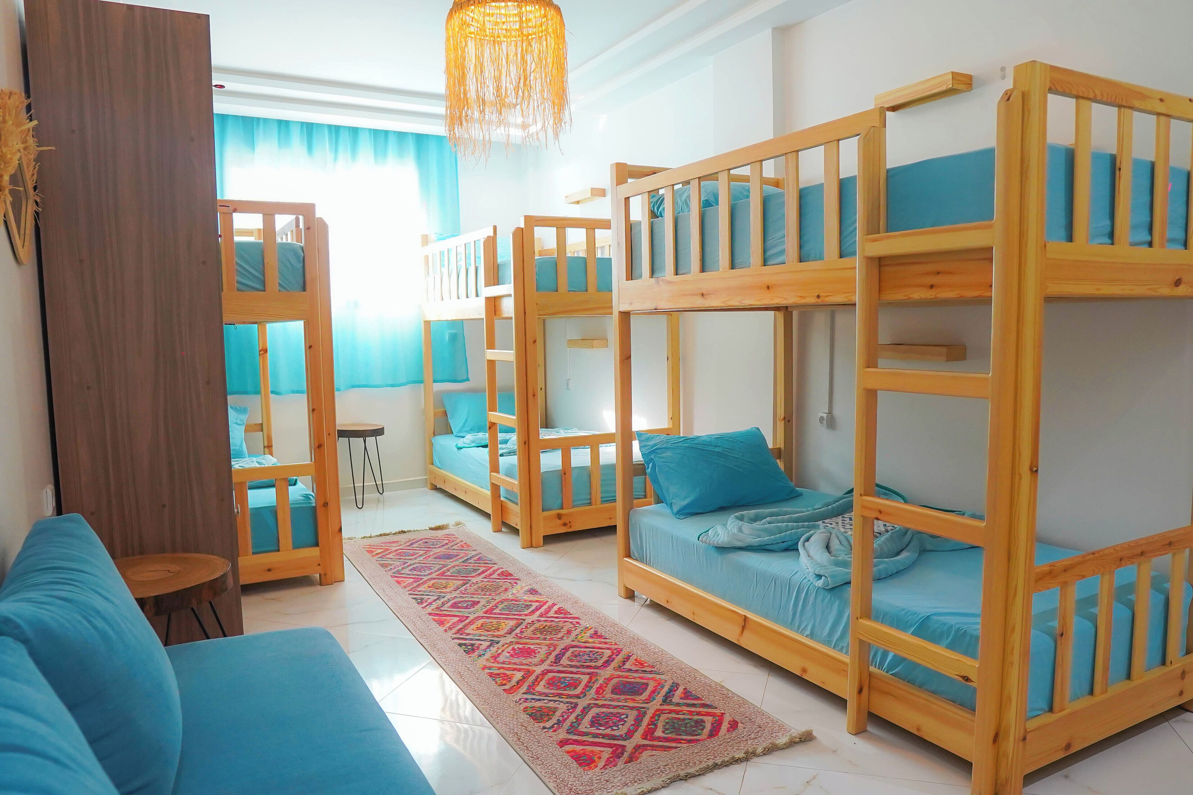 A room with bunk beds, a sofa, a patterned rug, and a hanging light fixture.