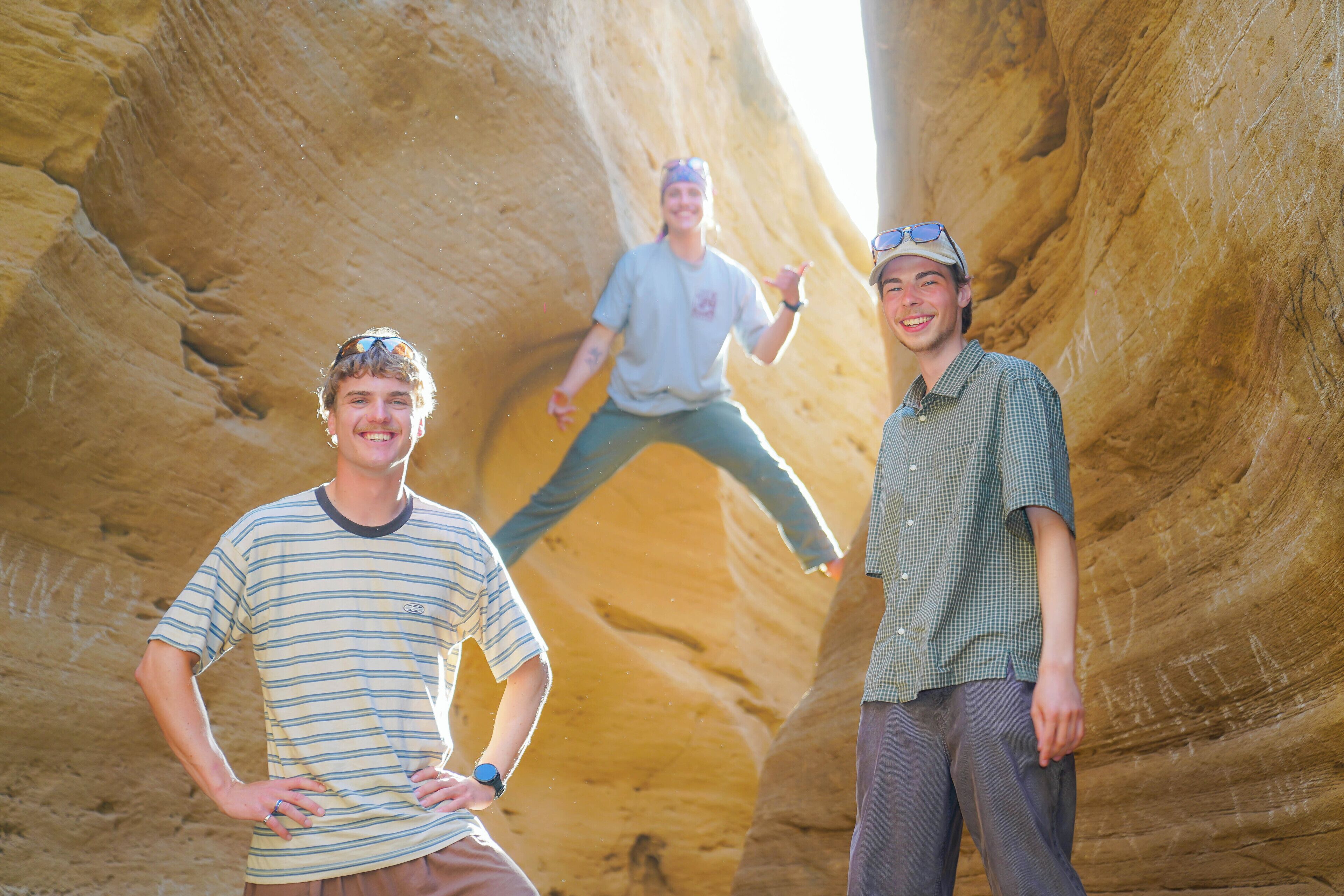 Tre persone in piedi presso una formazione rocciosa naturale.