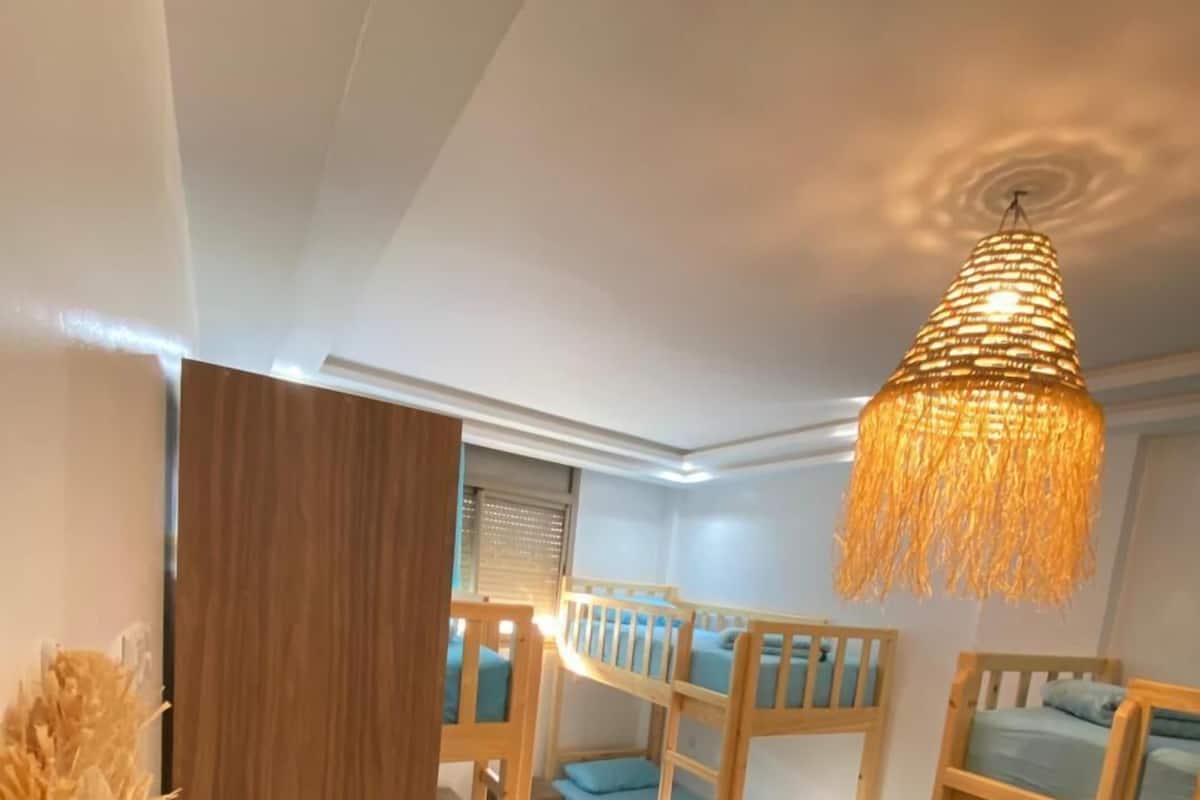 A room with bunk beds, a patterned rug, and a hanging light fixture.