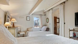 Une chambre d’hôtel comprenant un lit, un bureau avec une lampe, une chaise, une fenêtre donnant sur un paysage agréable et un téléviseur.