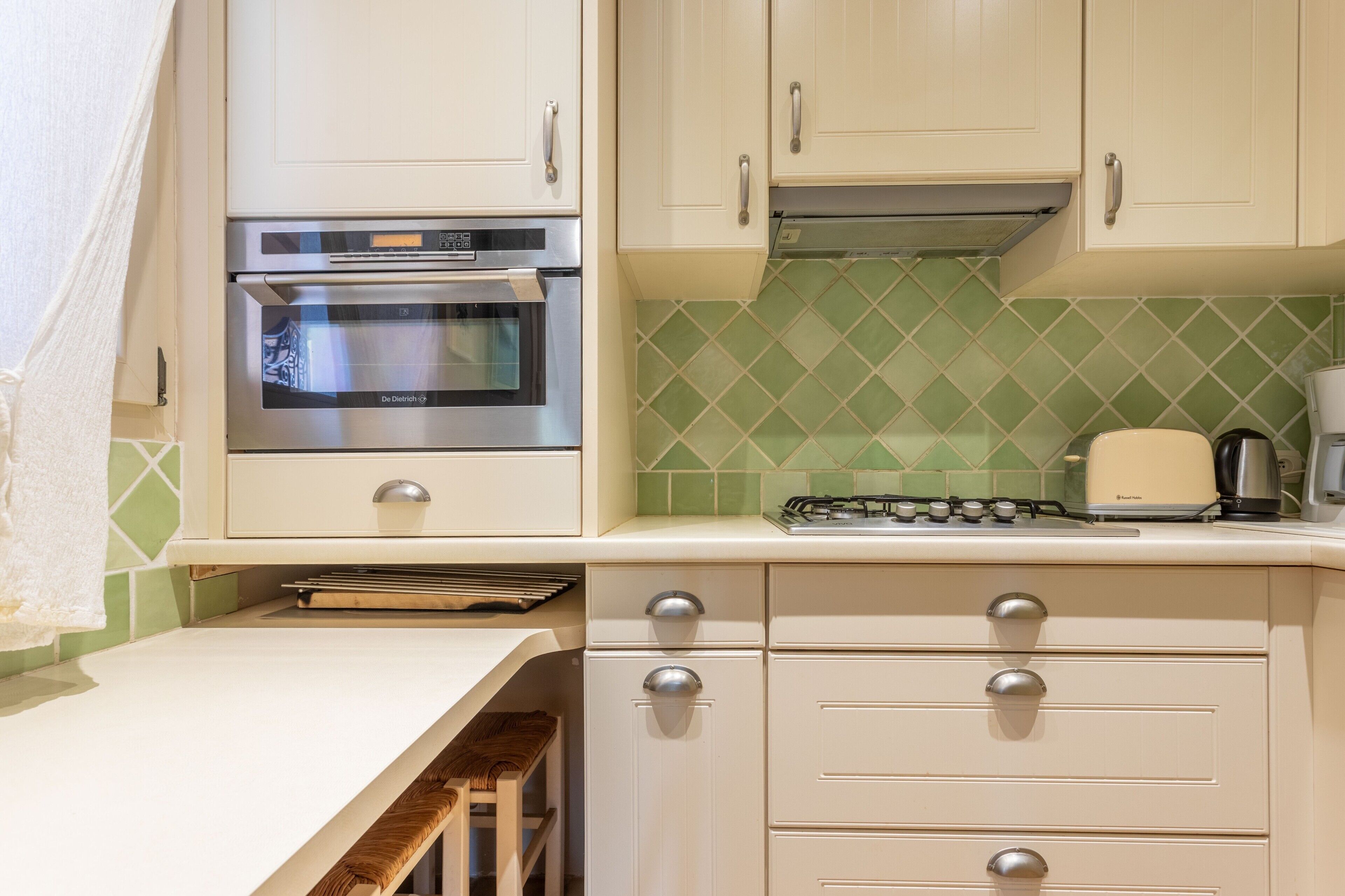 A kitchen with a built-in oven, a gas stove, and a coffee maker.