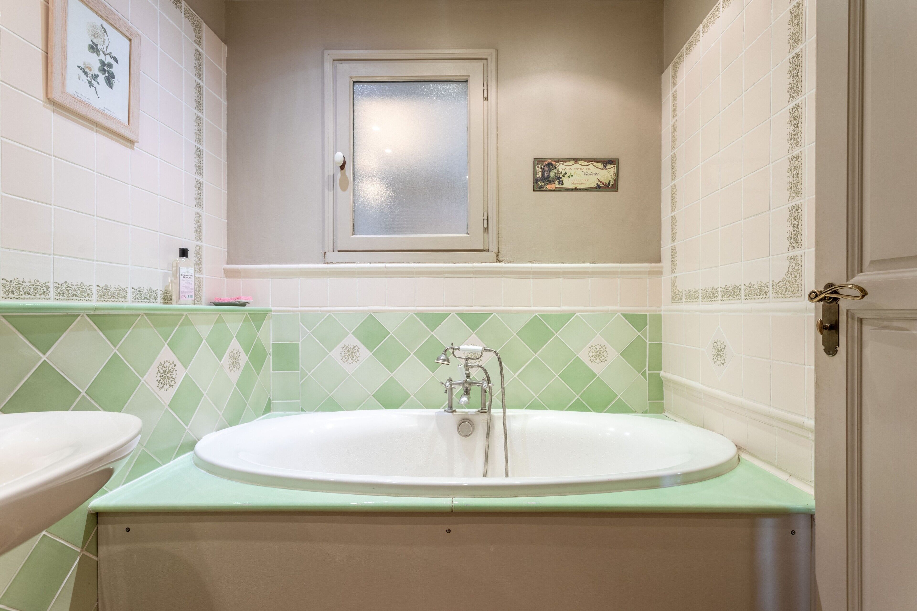 A bathroom with a bathtub, two sinks, a window, and decorative tiles.