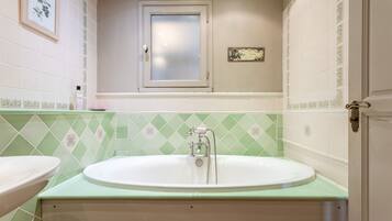 A bathroom with a bathtub, two sinks, a window, and decorative tiles.