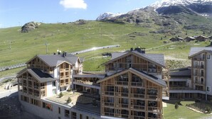 Un bâtiment moderne doté de grandes fenêtres et d’une façade en bois, qui se détache sur un paysage montagneux.