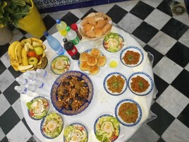 Una mesa con diferentes platos, como ensaladas, pan y un tazón de carne.