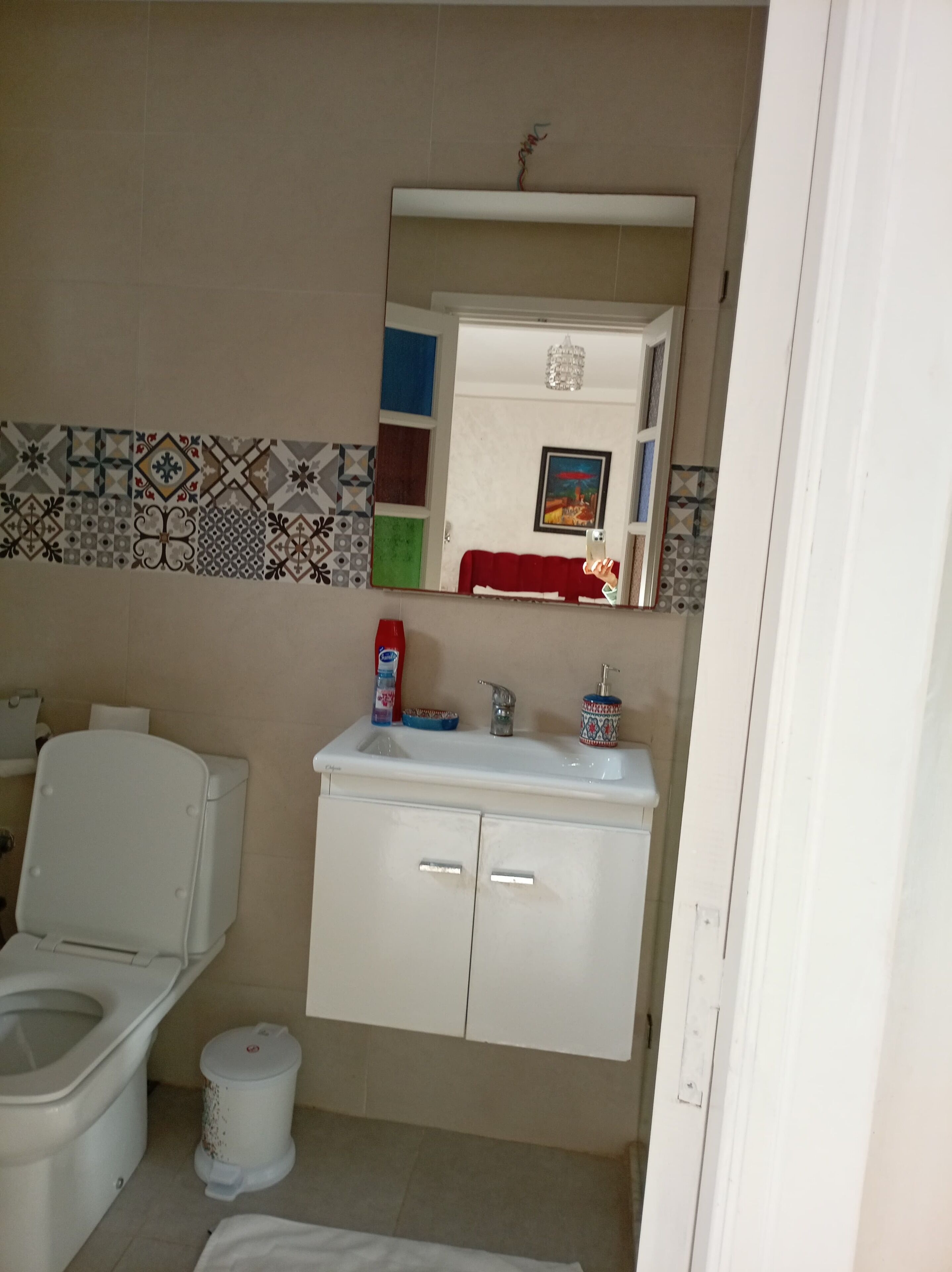 A bathroom with a toilet, sink, and cabinet.