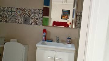 A bathroom with a toilet, sink, and cabinet.