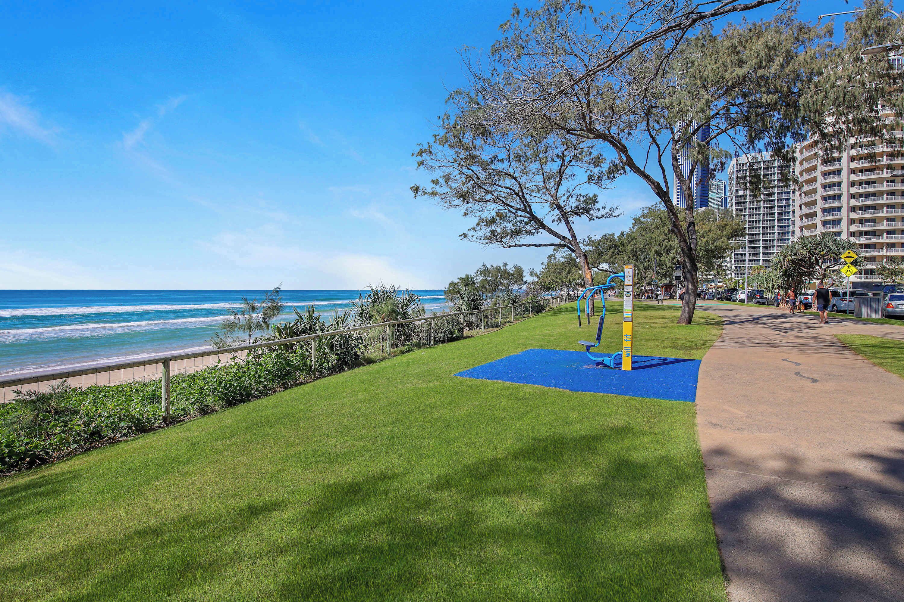 A grassy area with a blue mat, a metal fence, and a tree.