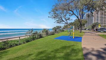 A grassy area with a blue mat, a metal fence, and a tree.