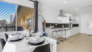 A modern kitchen with white cabinets, a black countertop, and a dining area with a white table set for four.
