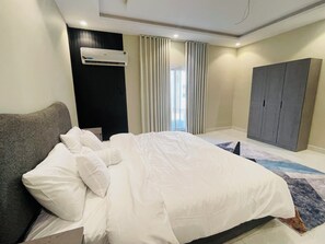 Een moderne hotelkamer met een groot bed, een kledingkast en een airconditioning.