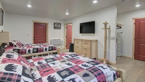 Quarto com duas camas, televisão, cabideiro e cômoda.
