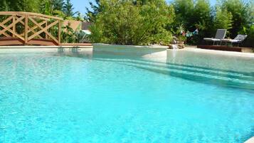 Une piscine aux eaux cristallines, dotée d’une terrasse en bois et de chaises longues.