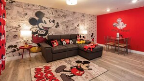 Un salon décoré sur le thème de Mickey Mouse, avec une grande fresque murale, un mur d’accent rouge et un panneau représentant Mickey Mouse.