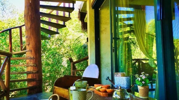 A wooden staircase leading to a balcony with a table set for breakfast, including a teapot, cups, and a plate of fruit. - La Casa de Mia Tulum (Tulum)