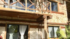 A stone building with large windows, a wooden balcony, and a tropical garden. - La Casa de Mia Tulum (Tulum)