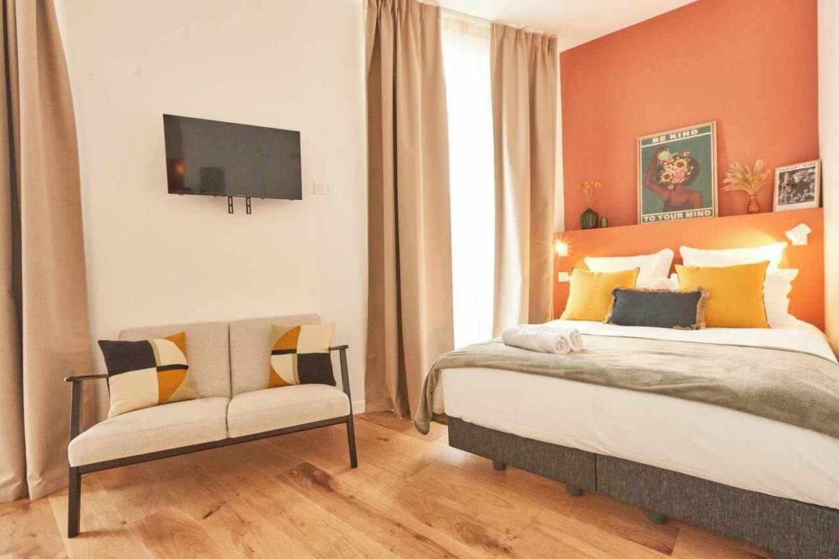 Ein Schlafzimmer mit einem Bett, einem Schlafsofa, einem Flachbildfernseher und einer Wand mit einem Poster.