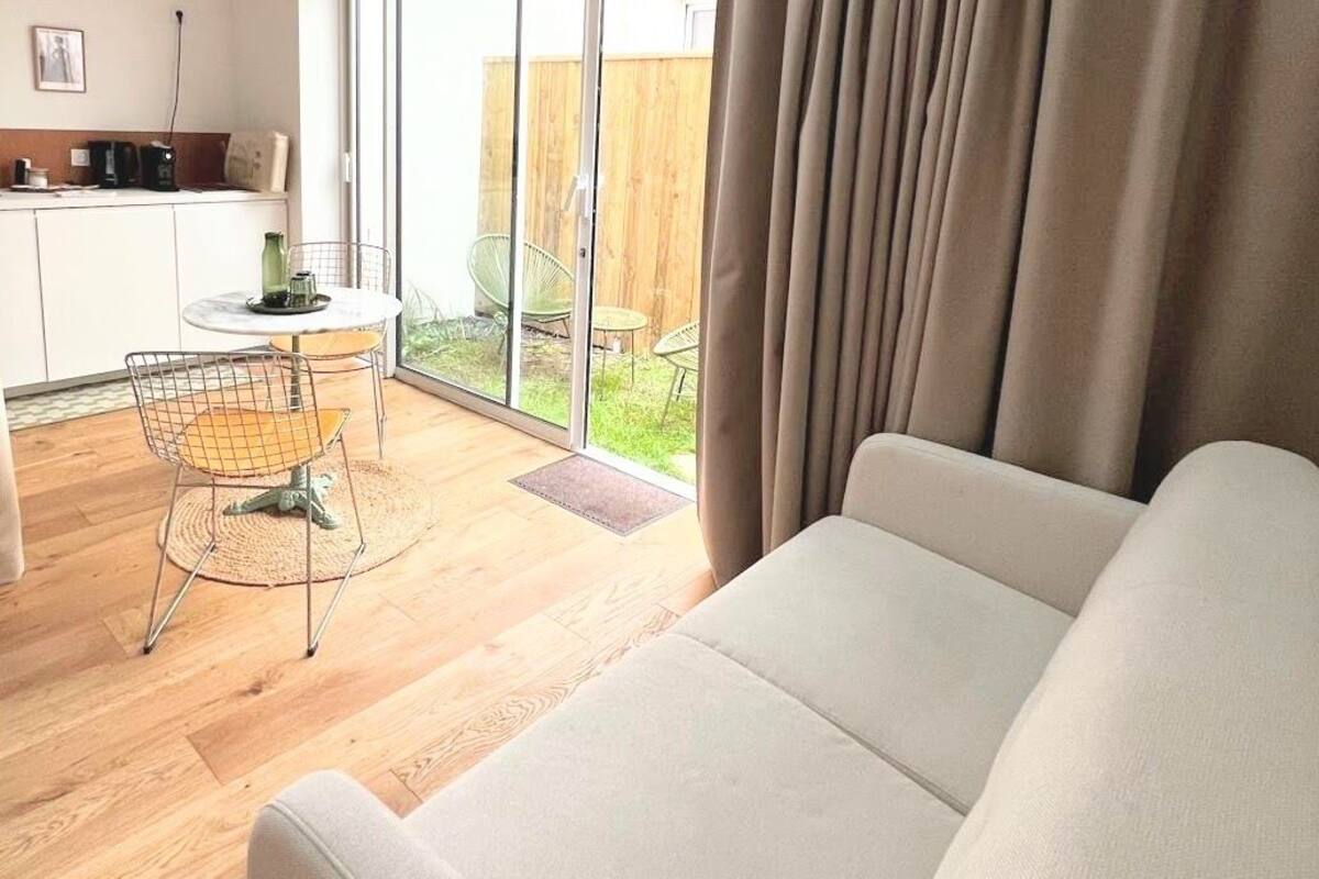 Ein modernes Wohnzimmer mit einer Couch, einem Esstisch mit Stühlen und einem durch eine Schiebetür einsehbarer Küchenbereich.