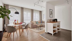 A modern living room with a dining area, a sofa set, a coffee table, and a small white desk with shelves. - Bella - Kaiserslautern (Kaiserslautern)