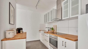 A modern kitchen with white cabinets, a wooden countertop, and a built-in oven. - Bella - Kaiserslautern (Kaiserslautern)