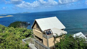 A coastal property with a wooden deck and a large window overlooking the sea.