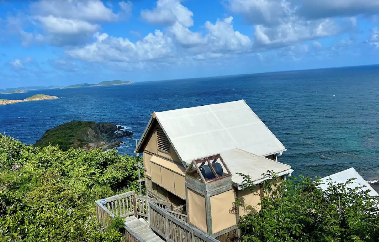 A coastal property with a wooden deck and a large window overlooking the sea.