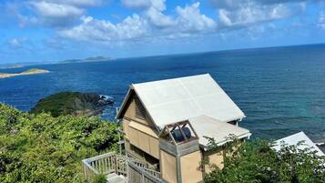 A coastal property with a wooden deck and a large window overlooking the sea.