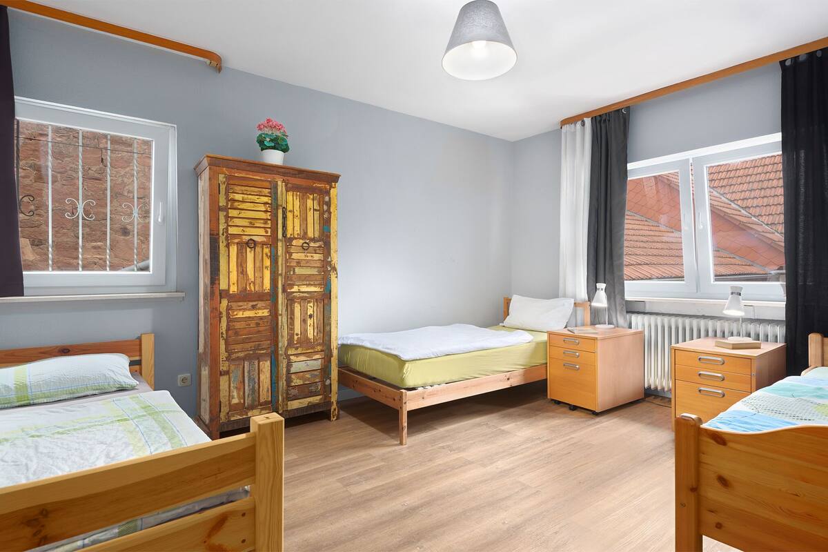 A bedroom with a wooden bed, a dresser, a cabinet, and a window with curtains.