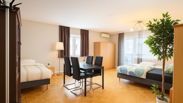 Una habitación de hotel moderna con una cama, una mesa de comedor con sillas, un escritorio pequeño, un armario y una planta en maceta.