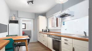 Una cocina compacta con armarios blancos, una encimera de madera y un horno empotrado.