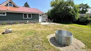 A house with a red roof, a front porch with a table and chairs, and a large metal barrel in the yard. - Lake Street Retreat - Walk to the beach! (Central Lake)