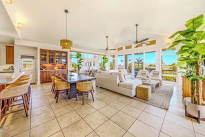 A spacious kitchen with a dining area, a living room with a sofa and coffee table, and large windows offering a view.