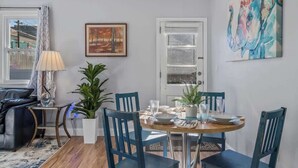 Een eethoek met een ronde tafel, blauwe stoelen en een potplant.