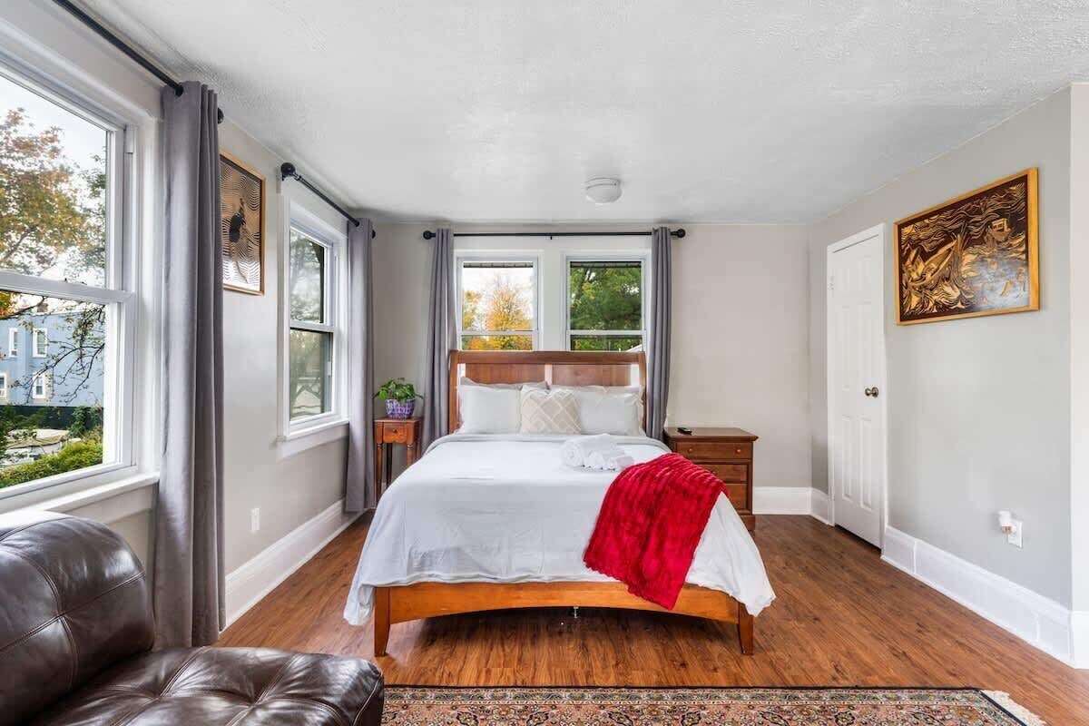 Bright master bedroom with a queen bed, soft linens, and views from every window.