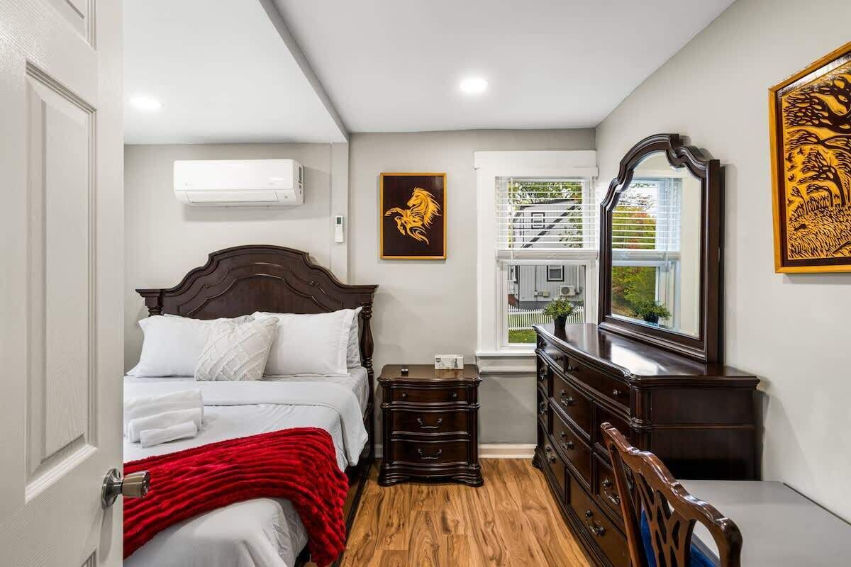 A bedroom with a wooden bed, a dresser, and a mirror.