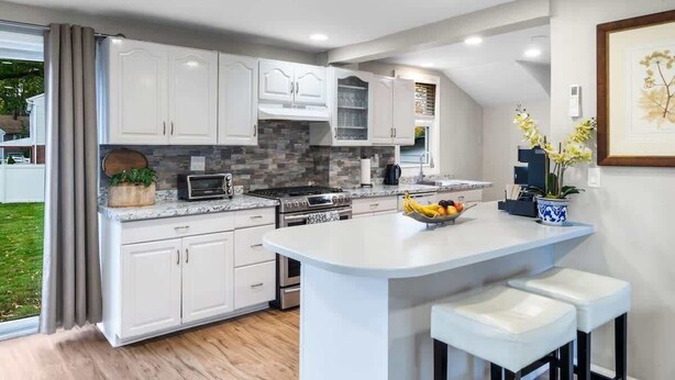 A modern kitchen with white cabinets, a granite countertop, and a central island with bar stools.