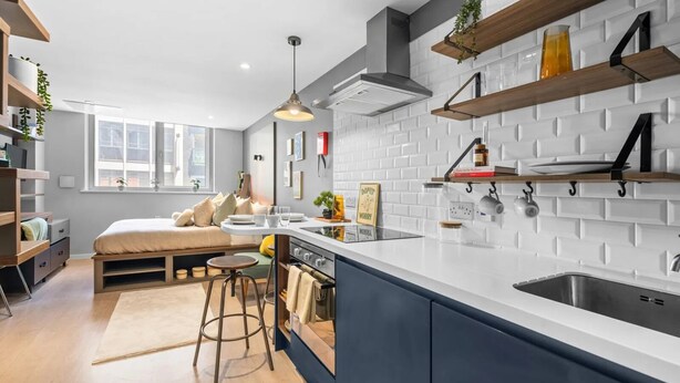 Una cocina moderna con isla integrada, azulejos blancos tipo metro, estantes de madera y una ventana que proporciona luz natural.