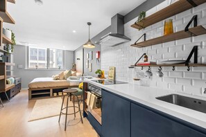 Een moderne keuken met een inbouw eiland, witte metrotegels, houten planken en een raam dat voor natuurlijk licht zorgt.