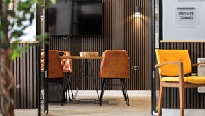 Un espacio privado para comer con una pared de madera, un televisor de pantalla plana y dos sillas.