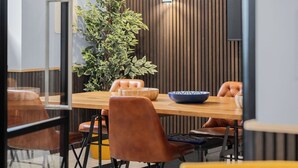 Un comedor moderno con una mesa de madera, sillas de cuero y una planta grande en maceta.