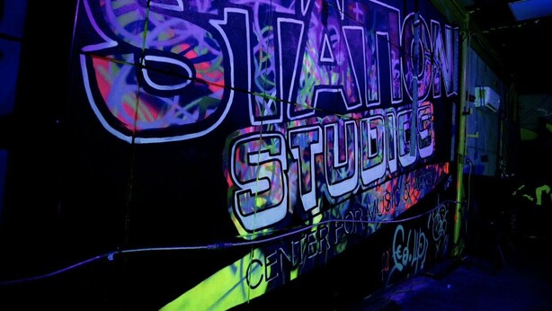 En neonskilte for 'Station Studios' med et farverigt, abstrakt design.