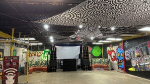 Et indendørs lokale med en scene, vægge med graffiti og et loft med et sort-hvidt mønster.