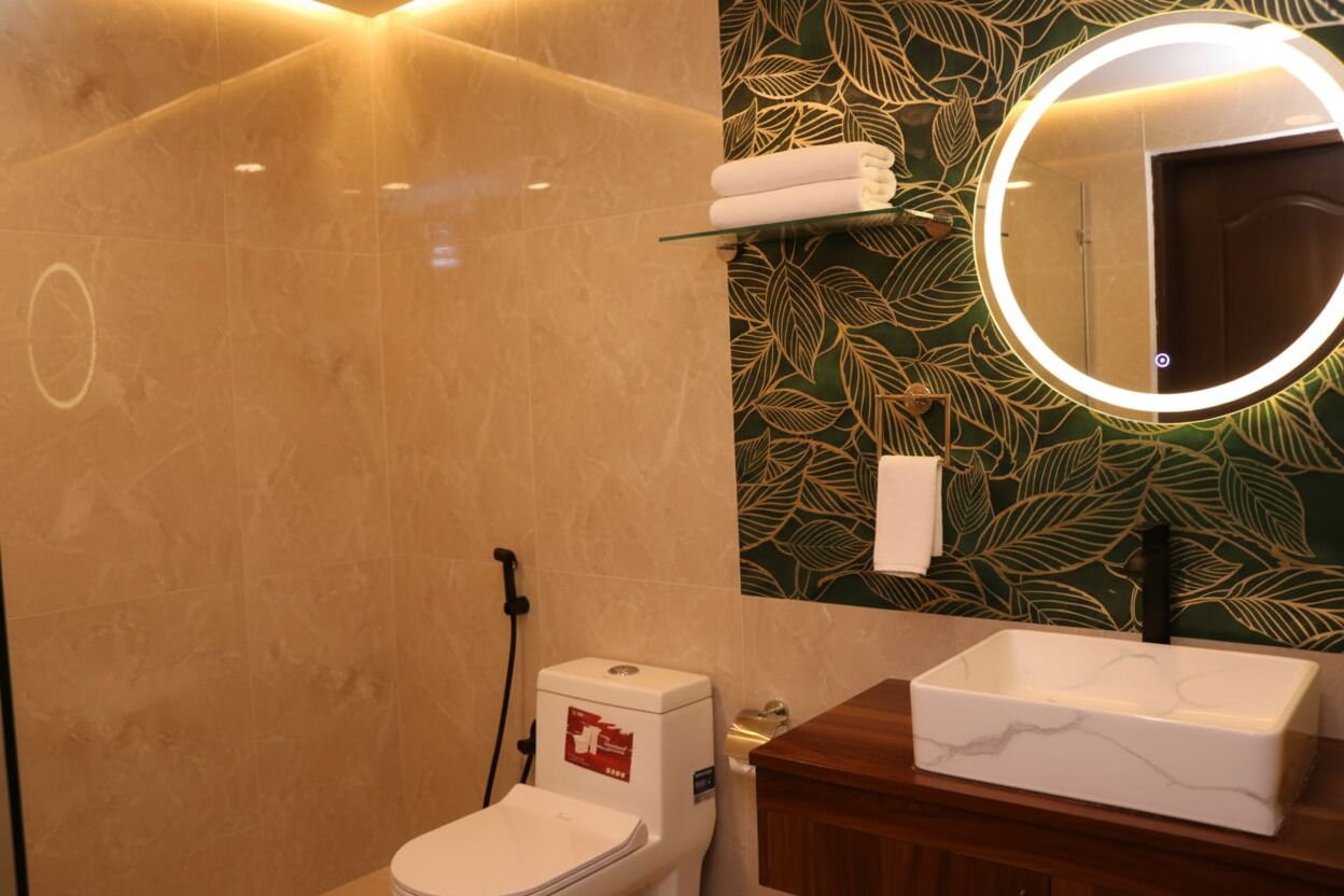 Une salle de bain moderne équipée de toilettes, d’un lavabo et d’un miroir avec un éclairage circulaire.